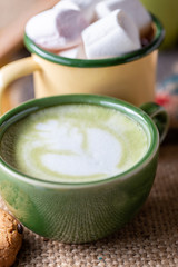 A cup of hot matcha latte on wooden floor