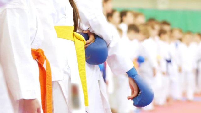 Hands of children standing in a row of karatekas in gloves