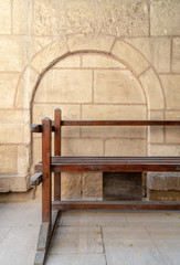 Wooden garden bench with background of stone bricks wall with arched niche at House of Egyptian Architecture historical building, Cairo, Egypt