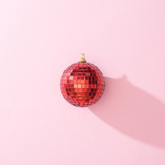 Red Christmas disco ball bauble on pink background. Minimal New year  party concept. Flat lay.