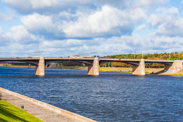 The new Volga bridge and city quay in Tver, Russia. Picturesque river landscape. Clouds in the blue sky. Green grass on the lawn. Summer or autumn Sunny day.