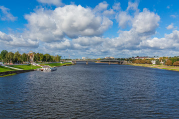 Volga river near Tver, Russia. The old Volga bridge on the horizon. Pleasure passenger boats at the pier. Picturesque river landscape. Sunny autumn day.