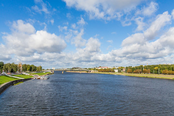 Obraz premium Volga river near Tver, Russia. The old Volga bridge on the horizon. Pleasure passenger boats at the pier. Picturesque river landscape. Sunny autumn day.