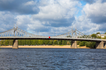 The old Volga bridge over the river and the beach in the town of Tver, Russia. Picturesque clouds in the sky. Summer or autumn Sunny day.