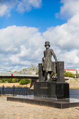 Monument to Russian poet Alexander Pushkin on the embankment in Tver, Russia. Volga river embankment. Autumn day. Picturesque landscape. Old Volga road bridge in the background.