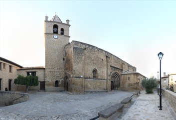 Obraz premium The Romanesque stone made Nicholas of Bari Church (Iglesia de san Nicolas de Bari), with the baroque bell tower and the front square in the small rural Aragonese town of Frago, Spain