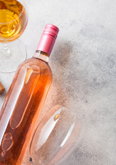 Bottle and glasses of pink rose wine with cork and corkscrew opener on stone kitchen table...