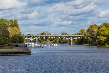 Fototapeta na wymiar Tvertsa river flows into the Volga river in Tver, Russia. Road bridge over the river and the city pier.