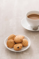Coffee. White porcelain cup of freshly brewed coffee top view close-up arranged with  biscuits, spoon and plate on light background