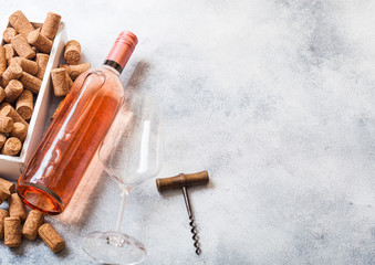 Bottle and glasses of pink rose wine with box of corks and corkscrew opener on stone kitchen table background. Top view. Space for text