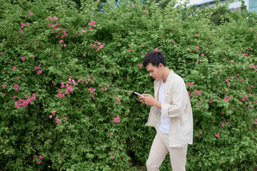 Young asian man in casual clothes on summer day and using smartphone for sending sms