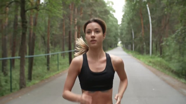 Dolly shot of sporty woman with fit body running in park