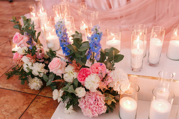 bouquet of pink roses and burning candles on an old white cloth surface, wedding decoration