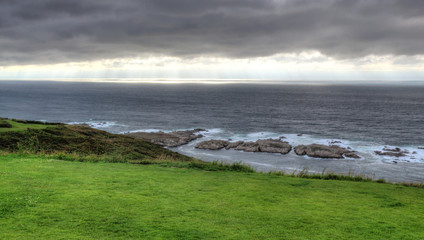 A landscape of a cloudy stormy sea and a grass lawn from Parque de Bens in Galicia capital city La...