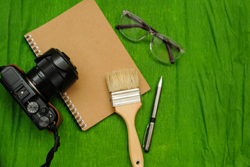 A notebook, a photo camera, glases, brush and pen