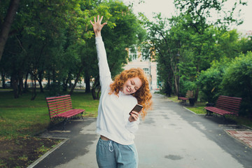 happy girl walking in park, holding smartphone