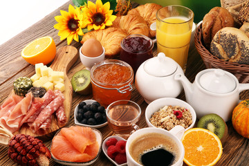 breakfast on table with bread buns, croissants, coffe and juice.