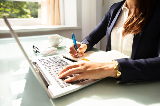 Close-up Of A Businesswoman's Hand Writing Note In Diary