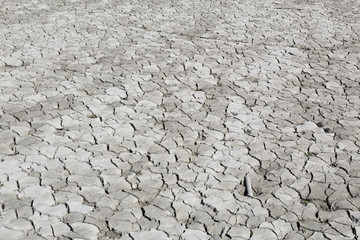 Dry cracked grey clay soil shot in perspective during a hot sunny day in the Mediano artifical lake...
