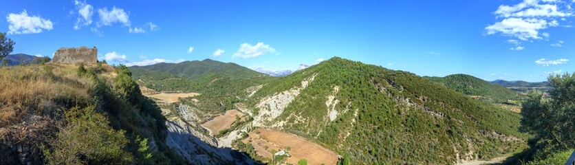 Fototapeta premium A landscape of cultivated fields, dense forest and mountains as seen from the castle of the rural medieval town of Boltaña, in the Spanish Aragonese Pyrenees