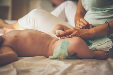 Mother with her baby at home. Mother changing diaper her little