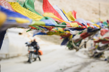 Motorcycle under Buddhist prayer flags blowing in the wind.