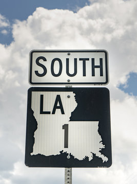 Bright White Clouds Frame A Sign Indicating Louisiana Highway Route 1