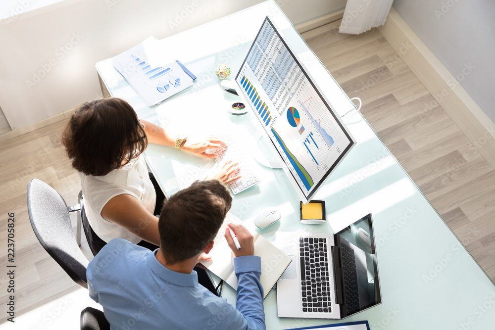Poster Two Businesspeople Analyzing Graphs On Computer