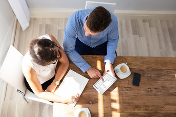 Two Businesspeople Examining Invoice On Digital Tablet