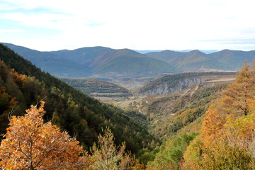 Blue cloudy sky and typical mountains and hills covered with forest met in autumn while hiking from the small Yebra de Basa town to Santa Orosia church on the Pyrenees mountains, Aragon, Spain