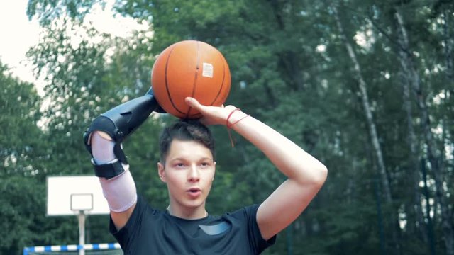 Teenage boy with a prosthetic hand is throwing a basket-ball.