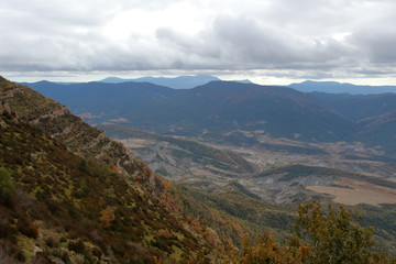 Blue cloudy sky and typical mountains and hills covered with forest met in autumn while hiking from the small Yebra de Basa town to Santa Orosia church on the Pyrenees mountains, Aragon, Spain
