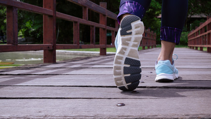 Plakat Sporty women walking on the wooden bridge, Close up of feamale sport shoes walking or jogging alone at park in the morning, Sports healthy lifestyle concept.