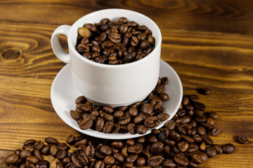 Coffee beans in white cup on wooden table