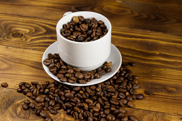 Coffee beans in white cup on wooden table