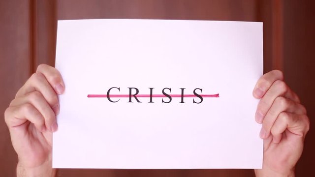 "Crisis" inscription crossed with red line in male hands