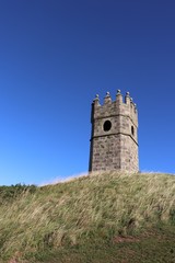 Old dovecot on hill against blue sky