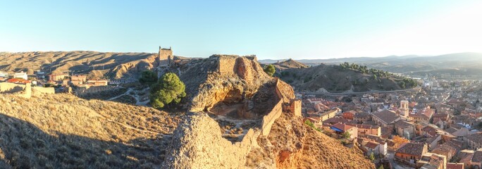 A landscape of the ancient Daroca fortifications and defensive walls on a hill, at the sunset, in...