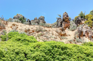 A landscape of the green trees and bushes, together with the red and brown rocks, in the Muel city park during spring, Spain