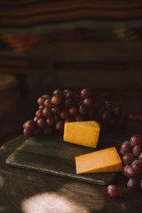 close-up shot of slices of cheese with grapes on cutting board