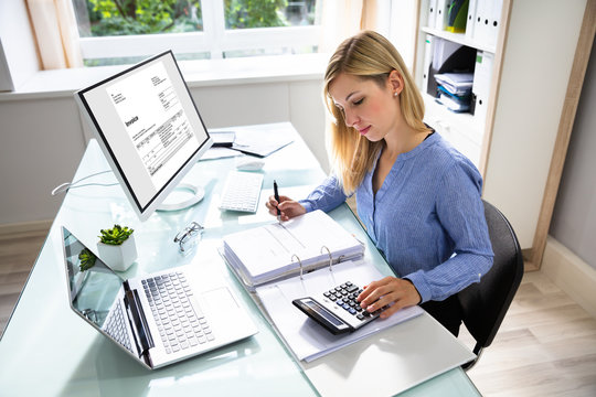 Young Businesswoman Calculating Bill In Office