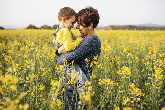 Mother standing in canola field with her son