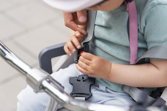 Mother and daughter, daughter sitting in children's seat and fastening seat belt