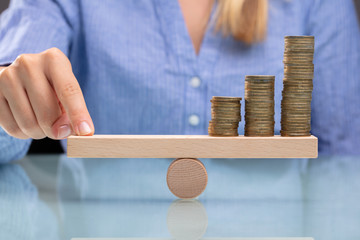 Businesswoman Balancing Stacked Coins With Finger