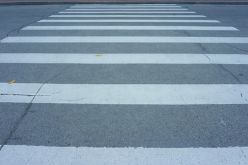 pedestrian crossing, cracks on asphalt, two yellow leaves