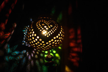 Lamp from coconut, souvenir from the sea from Thailand. Round slots in the coconut glow from the...
