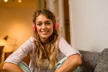 Woman with headphones sitting on sofa in her flat