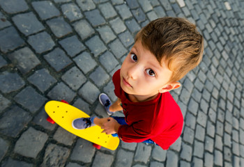 Little boy on skateboard looks with big eyes at the camera © concept w