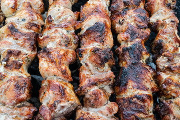 Frying pork on a skewer over a brazier. Turning meat over coals. Appetizing shish kebab. Delicious barbecue.