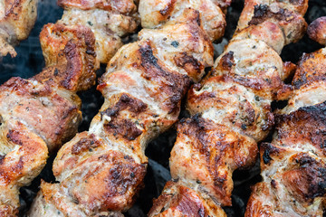 Frying pork on a skewer over a brazier. Turning meat over coals. Appetizing shish kebab. Delicious barbecue.